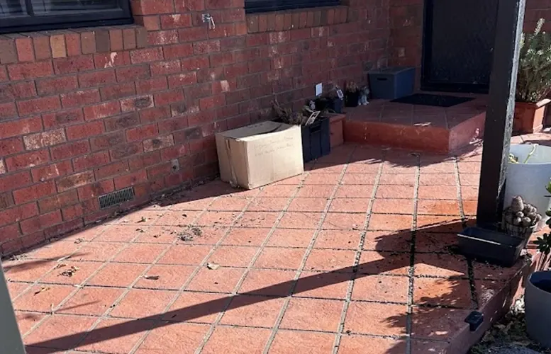 A swept brick porch and paved area after boxes and household rubbish were removed