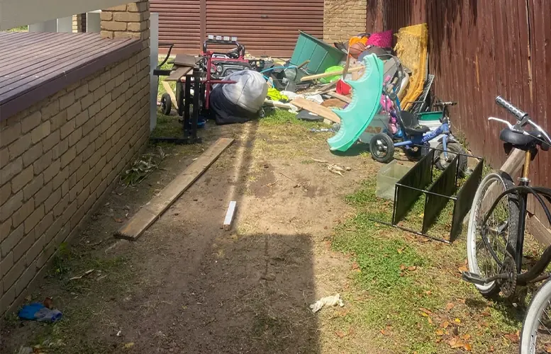 Before: a side passage crowded with bikes, toys, timber and outdoor clutter