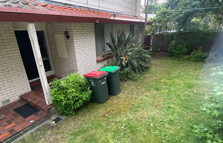 After: the same front lawn cleared, with only the wheelie bins remaining